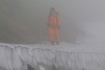 ガスの中雪渓を渡る